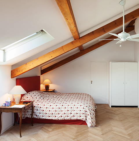 cozy bedroom with window natural light featuring a bed with patterned pillows and knitted throw blankets two decorative plants and bedside lamp